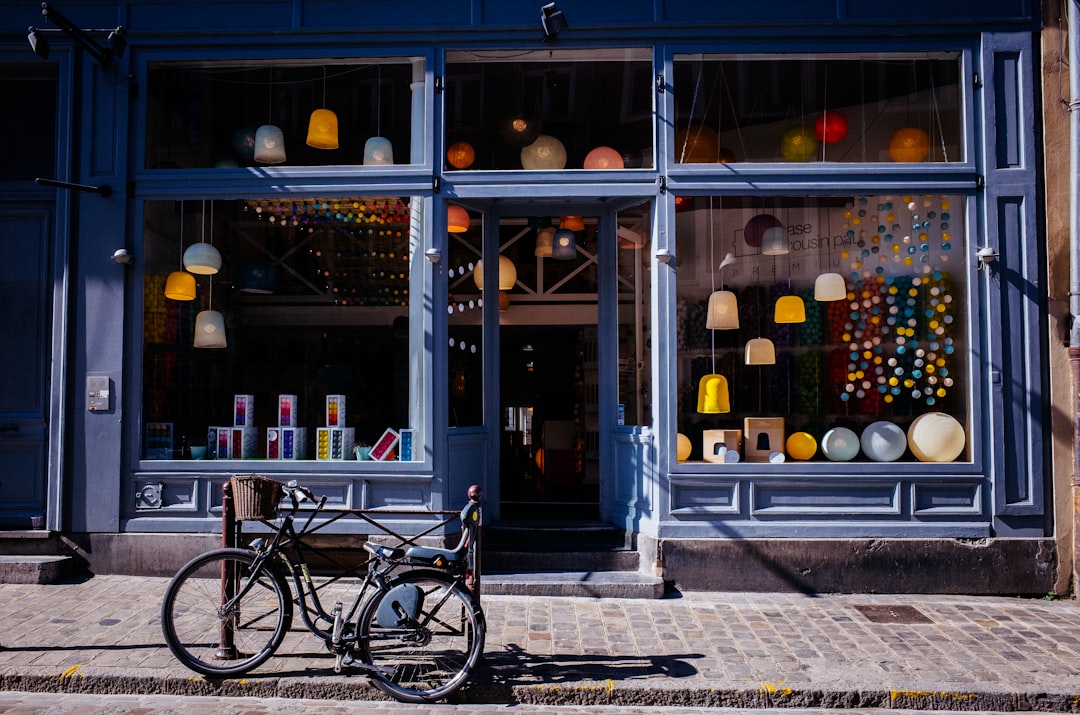 A bicycle parked on a cobblestone sidewalk in front of a lamp shop